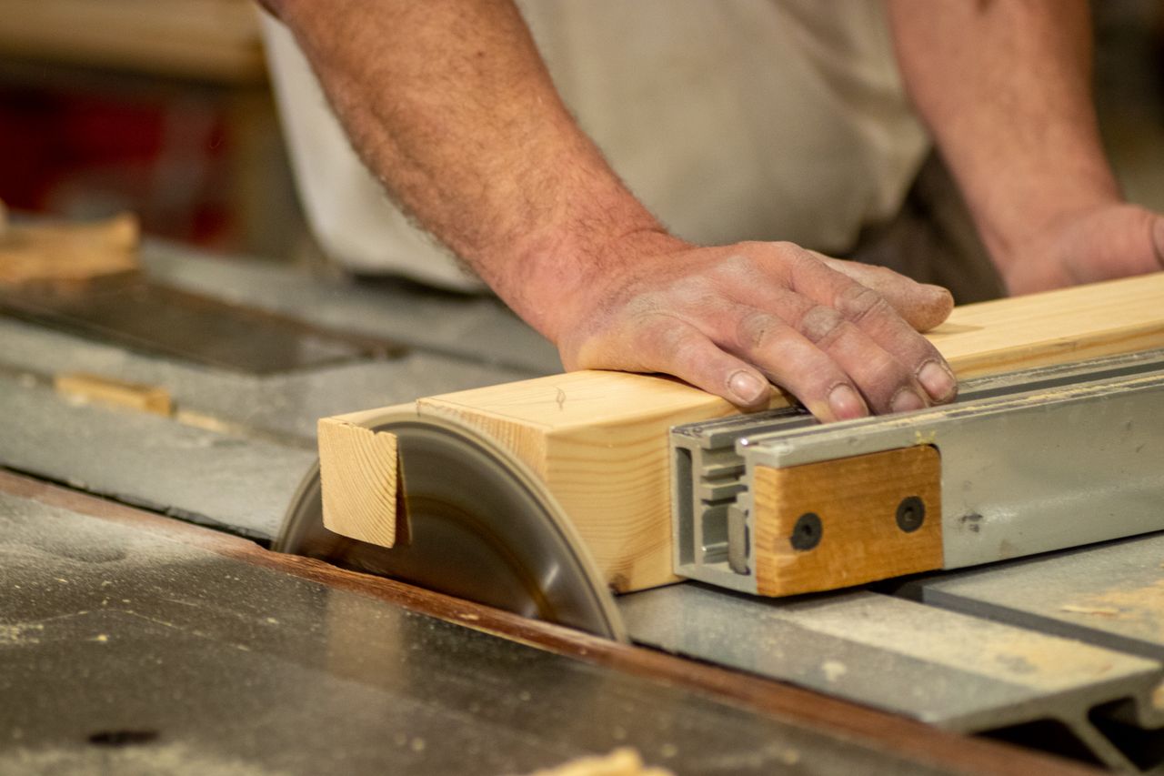 services-02 Hands of a carpenter cutting wood on a table saw, showcasing craftsmanship and precision.