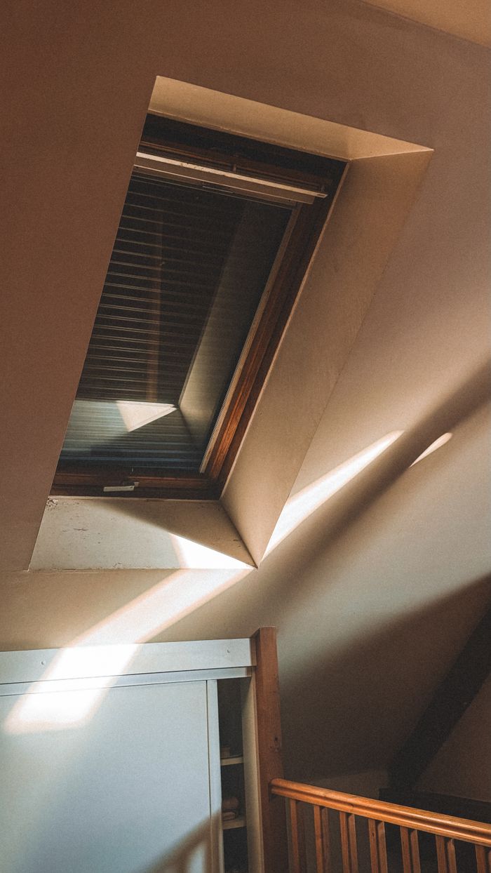 services-03 Warm sunlight casting through an attic window, illuminating wooden interior details.